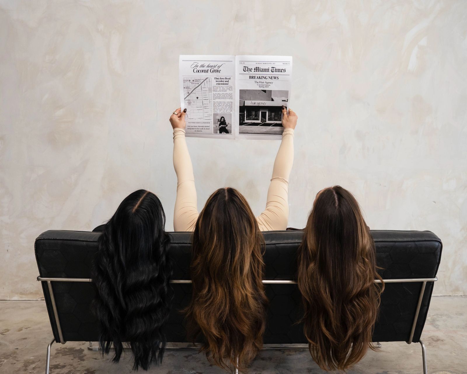 Three clients from behind showing rich balayage, holding a mock Miami Times front page for The Hair Agency